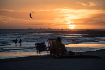 Silhouette people on beach against sky during sunset