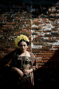 Portrait of woman standing against brick wall