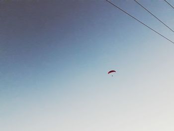 Low angle view of person paragliding against clear sky