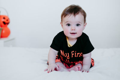 Portrait of cute girl sitting on bed at home