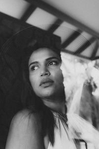 Low angle view of thoughtful woman looking away seen through glass window