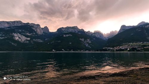 Scenic view of lake by mountains against sky