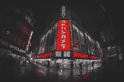 People on illuminated street amidst buildings in city at night