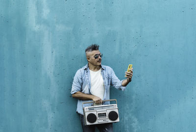 Full length of man standing against blue wall