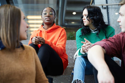 Multi-ethnic students talking while sitting on steps at university