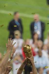 Cropped hands of people holding trophy on field