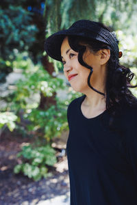 Middle-aged japanese woman in black straw sun brim hat, summer park