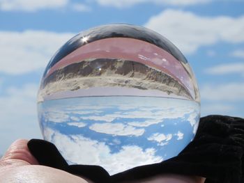 Close-up of hand holding glass against sky