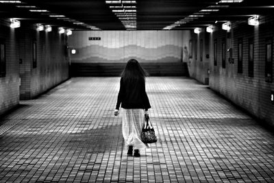 Rear view of woman with bag walking in underground walkway