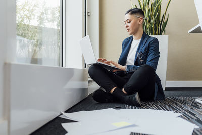 Female professional using laptop while sitting on office floor