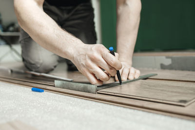 Man marking laminate panel on floor at home