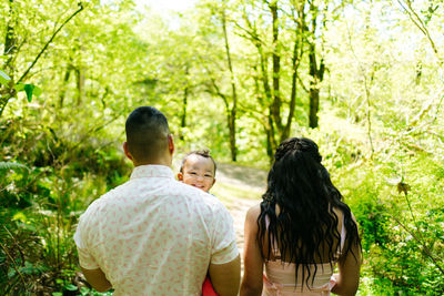 View from behind of a family of three walking through the forest
