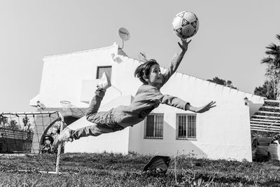 Low angle view of man jumping on built structure against sky