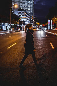 Girl with face mask crossing the street at night.