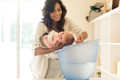 Portrait of woman holding baby at home