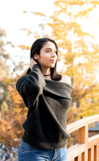 Beautiful young woman standing in park during autumn