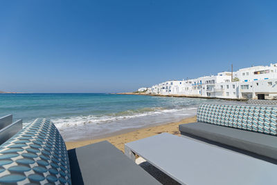 Scenic view of sea by buildings against clear blue sky