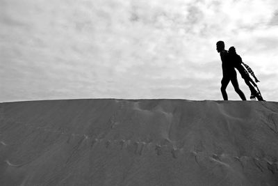 Model with costume wing walking at desert against cloudy sky