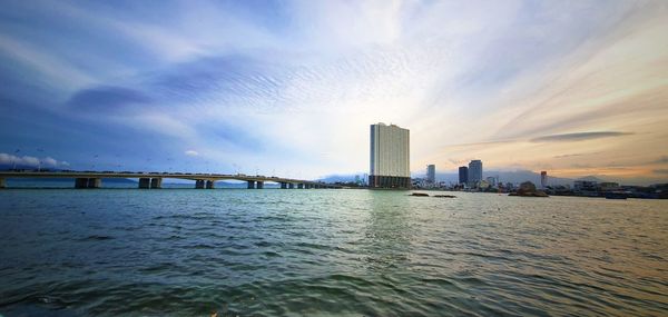 Bridge over sea by buildings in city against sky