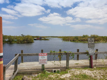 Information sign by lake against sky