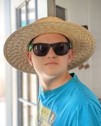 Portrait of teen boy wearing straw hat and sunglasses