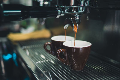 Close-up of coffee cup on espresso maker in cafe