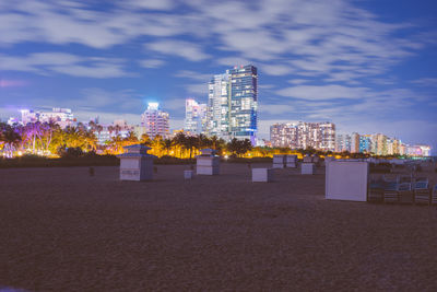 Illuminated modern buildings in city against sky
