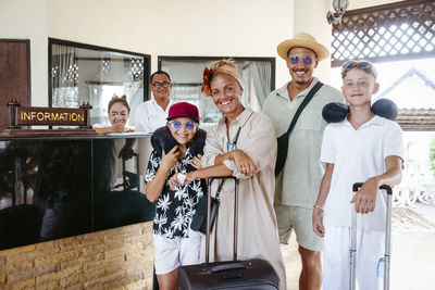 Portrait of happy family with receptionists standing in tourist resort