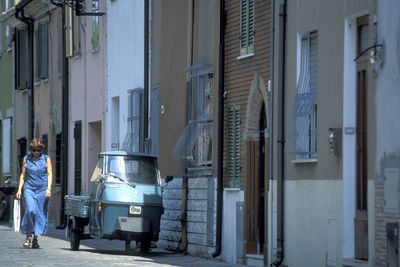 Man walking on alley amidst buildings in city