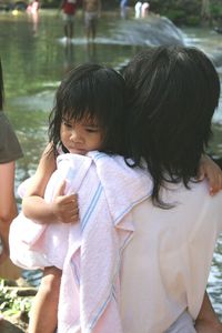 Rear view of mother carrying daughter by lake