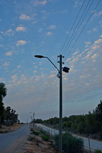 Street lights by road against sky