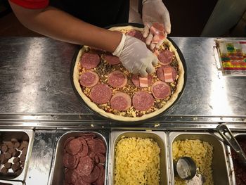 Cropped image of man preparing pizza in commercial kitchen