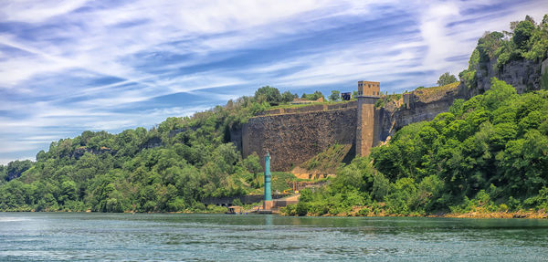 View of castle by river against sky