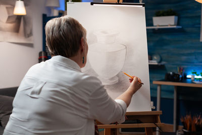 Rear view of woman sketching on canvas