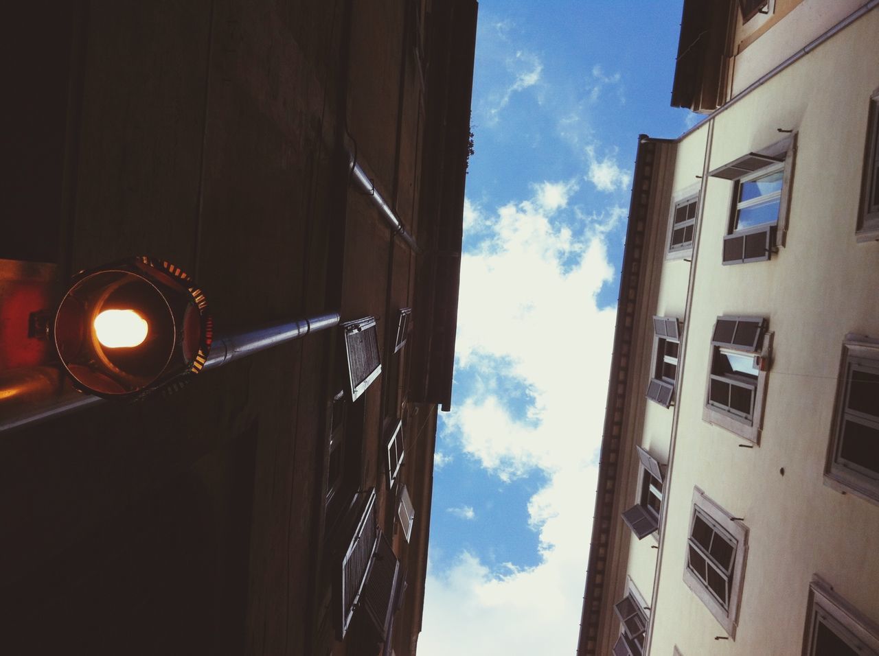 building exterior, architecture, built structure, sky, low angle view, building, window, city, street light, transportation, illuminated, residential building, residential structure, lighting equipment, street, outdoors, mode of transport, no people, cloud - sky, cloud