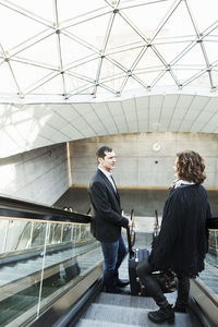 Business people moving down escalator in railway station