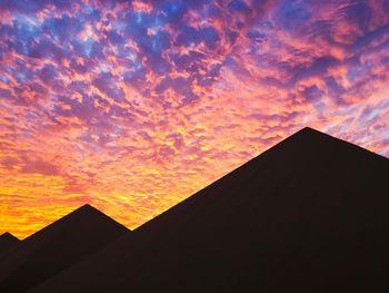 Low angle view of silhouette building against orange sky