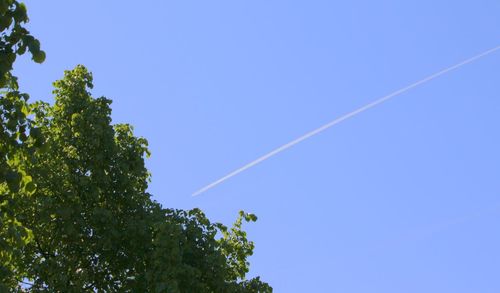 Low angle view of vapor trail against clear blue sky