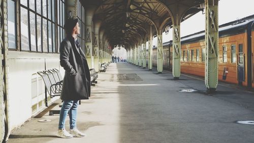 Side view of young man standing at railroad station platform