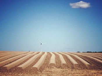 Wind turbines on field against clear sky