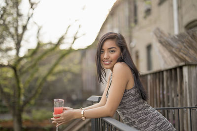 Young woman with a cocktail on her balcony