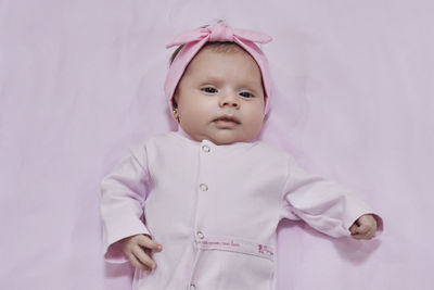 Portrait of cute baby girl looking away against black background