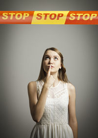 Portrait of young woman standing against wall