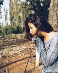 Side view of thoughtful young woman standing by fence