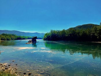 Scenic view of lake against clear blue sky