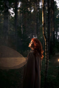 Rear view of woman standing in forest