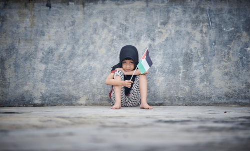 Full length of boy standing against wall