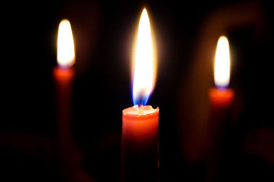 Close-up of burning candles in darkroom