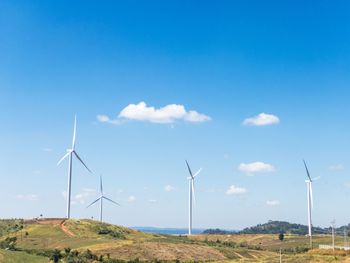 Wind turbines on field against blue sky