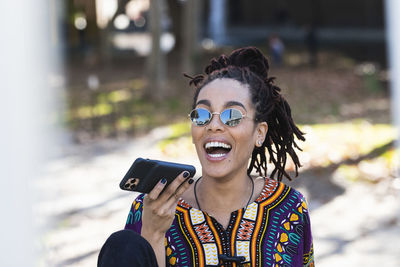 Portrait of smiling young man using smart phone outdoors